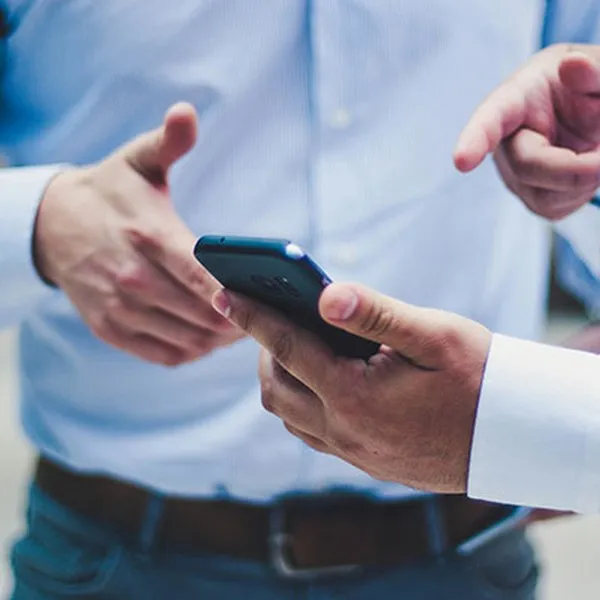 Dva lidé v košilích se společně dívají do smartphonu