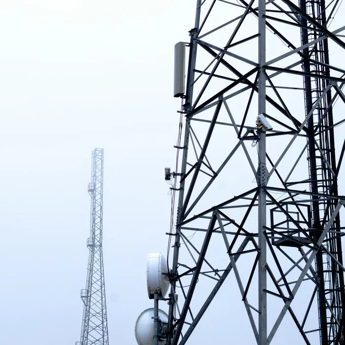 Telekomunikační stožáry proti bledé obloze